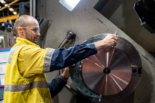 HMG employee measuring hydraulic cylinder rod on CNC machine