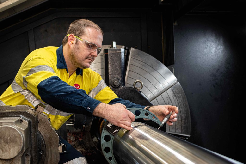 Hydraulic Cylinder rod being measured while on a lathe